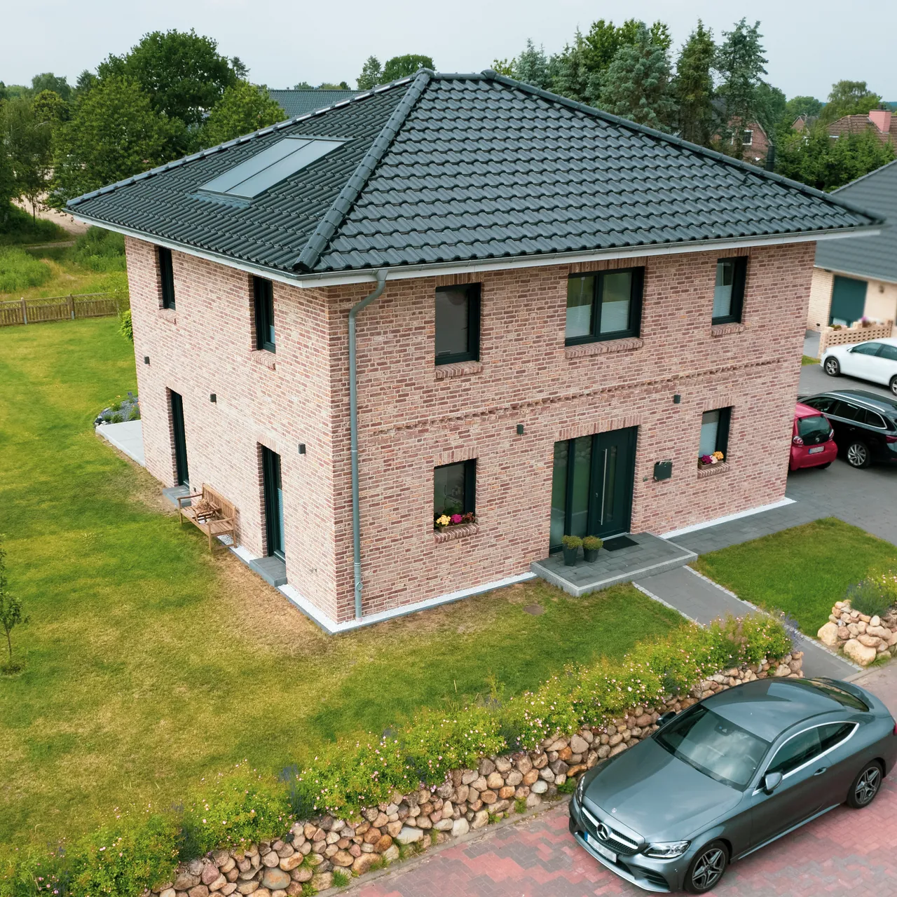 Neubau-Stadtvilla aus rotem Klinker mit Walmdach aus der Luft