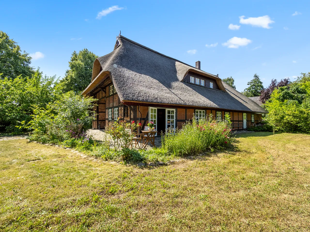 Außenansicht eines reetgedeckten Fachwerkhauses mit Garten