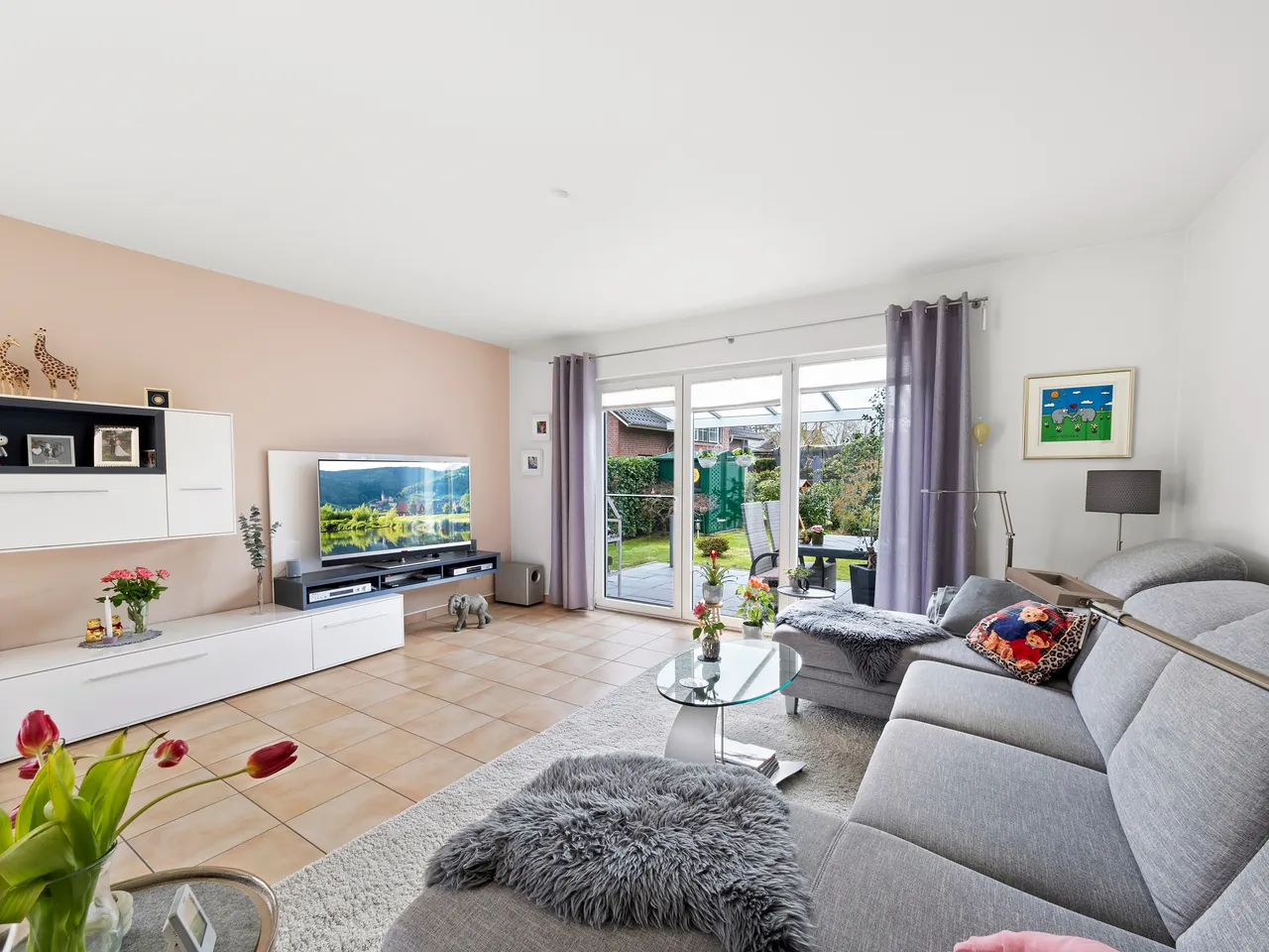 Helles Wohnzimmer mit grauem Sofa und Fensterfront zur Terrasse